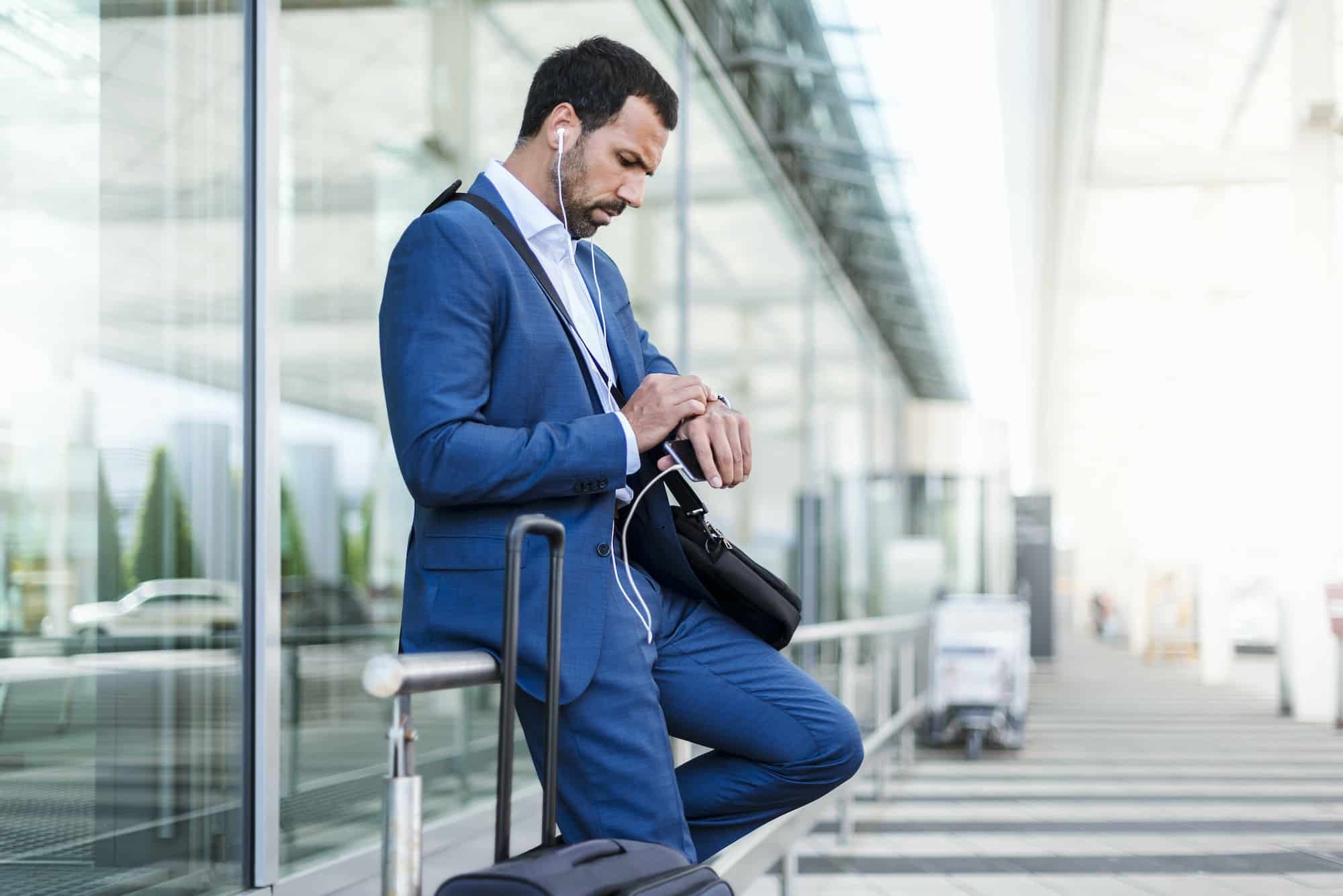 Businessman at airport, looking on watch