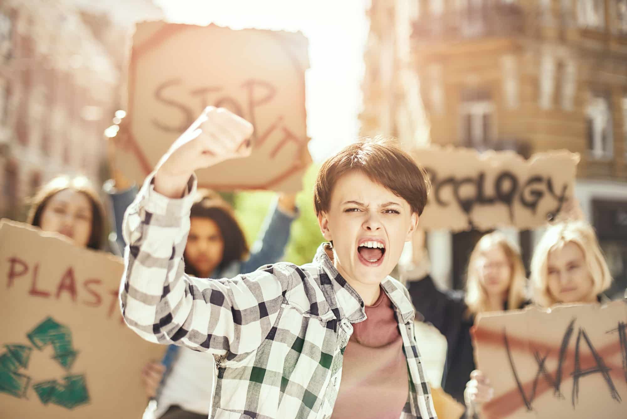 Fighting for clean earth. Young and strong woman is protesting for ecology with group of female