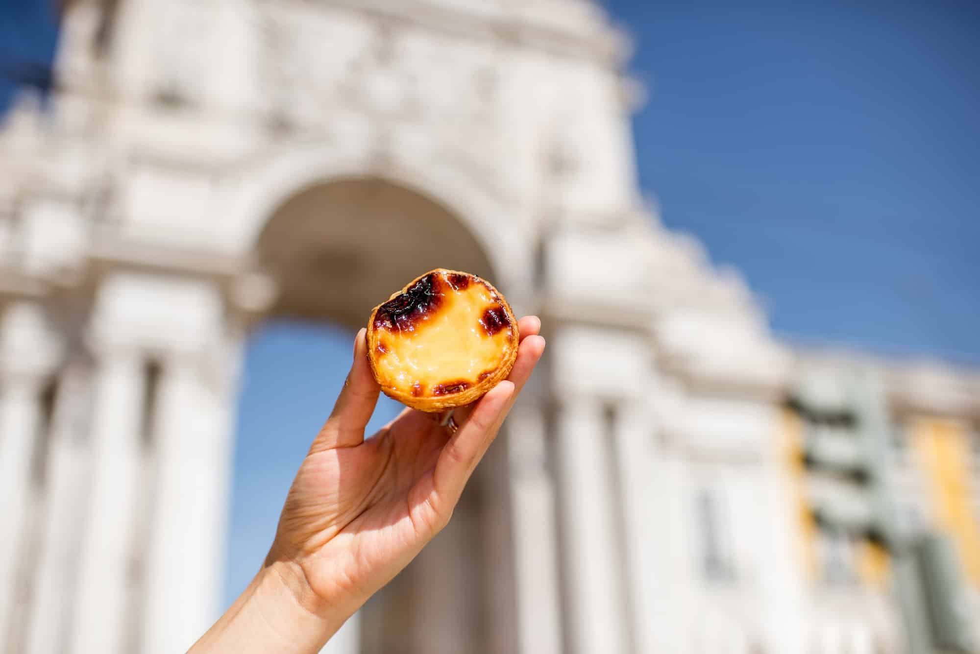 Holding pastel de Nata cake outdoors