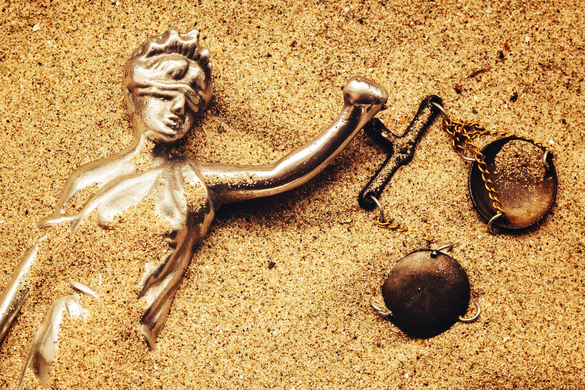 Statue of lady Justice buried in sand