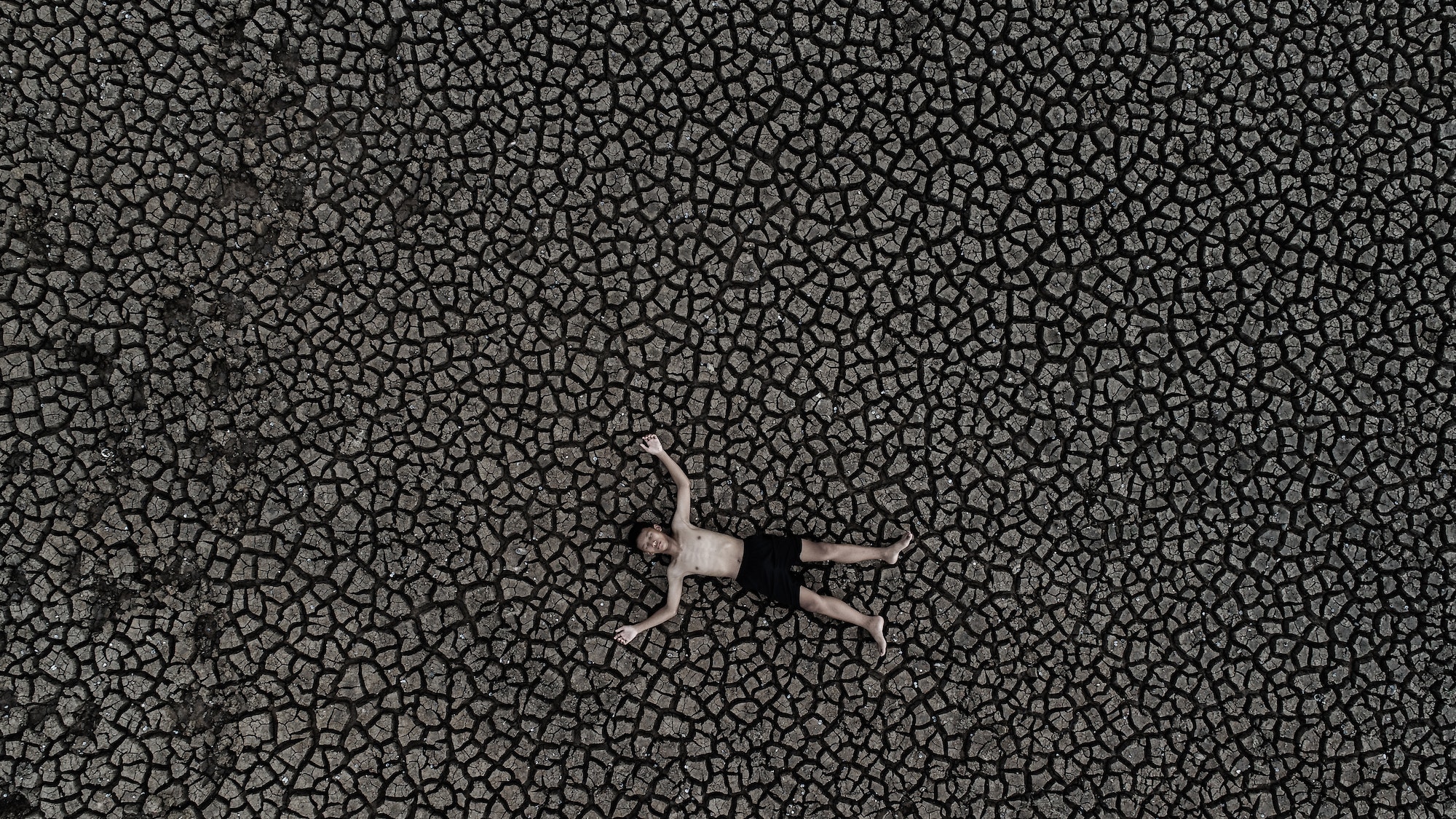 Boys sleep on dry land with dry and cracked soil, global warming