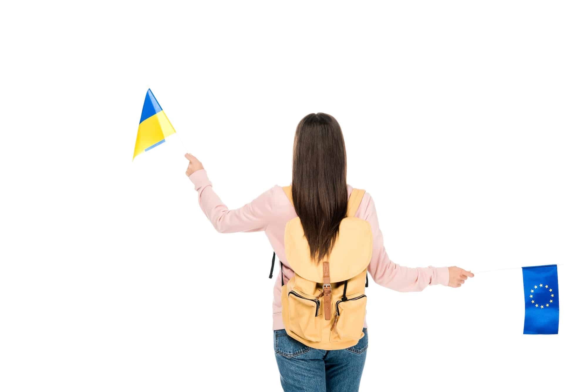 back view of student with backpack holding Ukrainian and European flags isolated on white