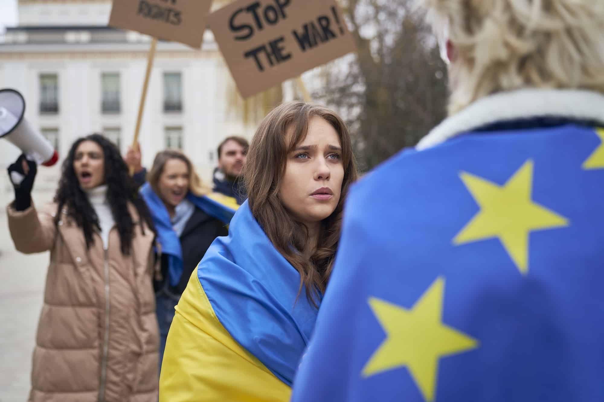 Man and woman covered with EU and Ukraine flags standing face to face and talking