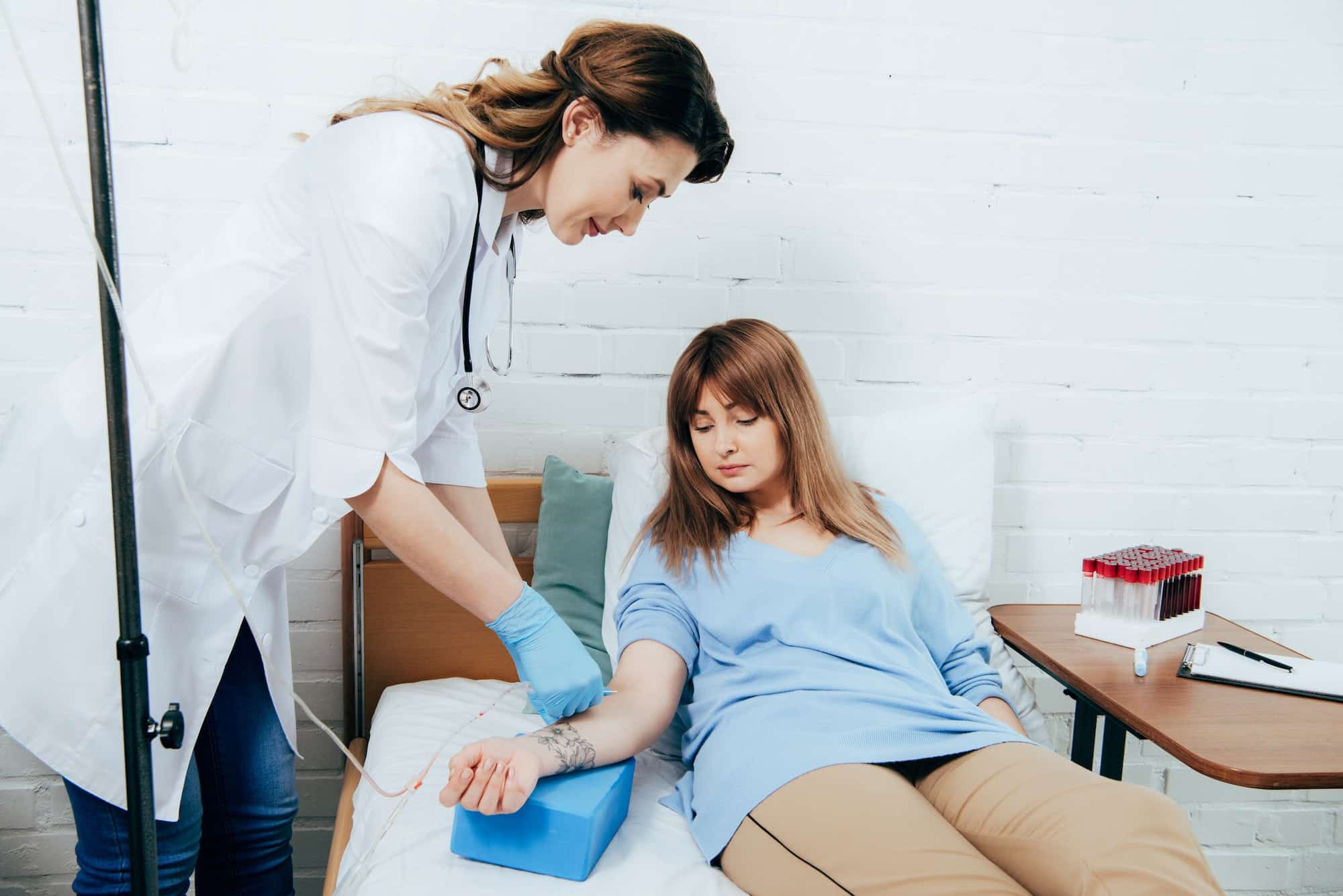 doctor in white coat and donor donating blood in hospital