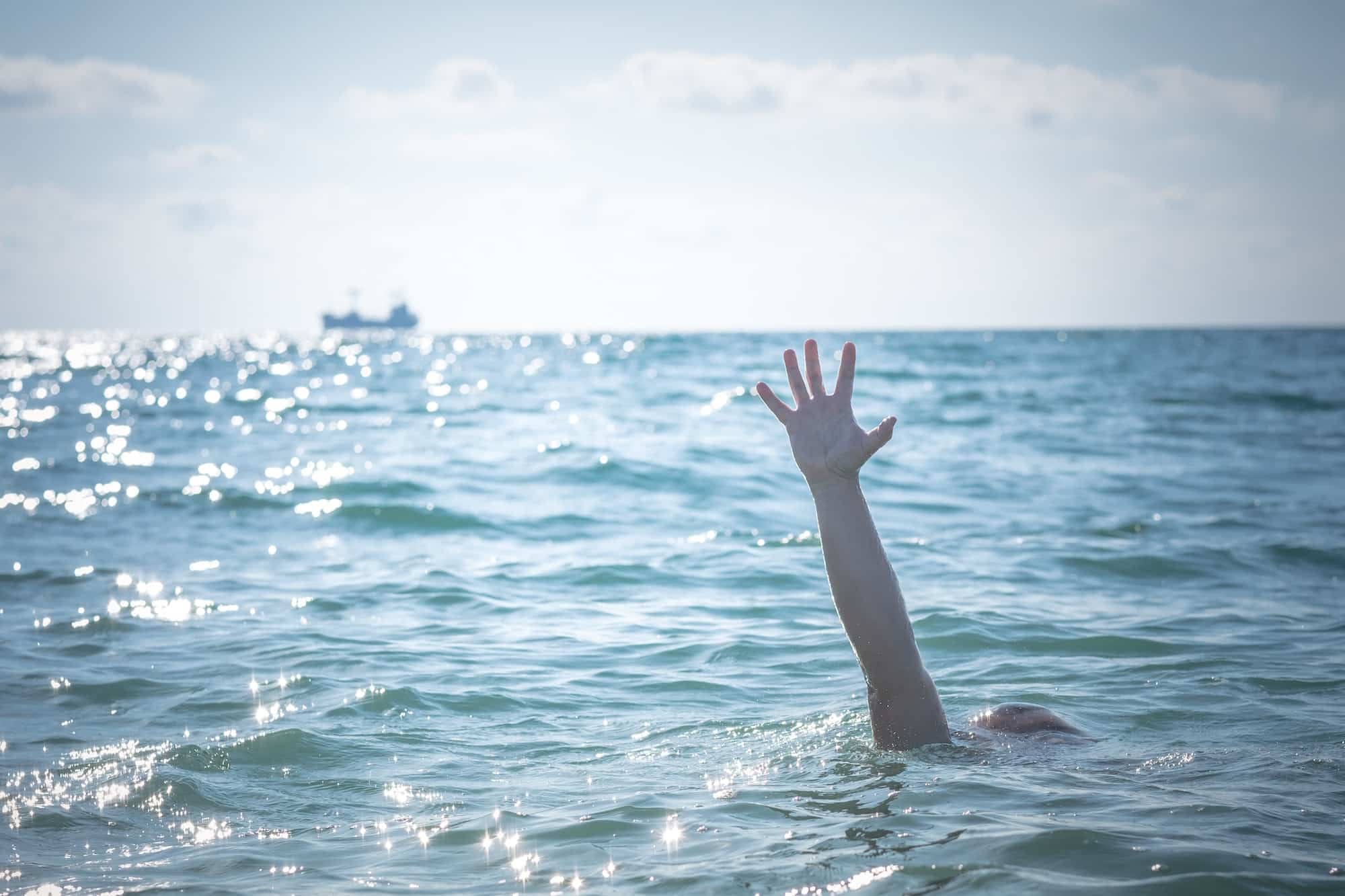 single hand of drowning man in sea asking for help