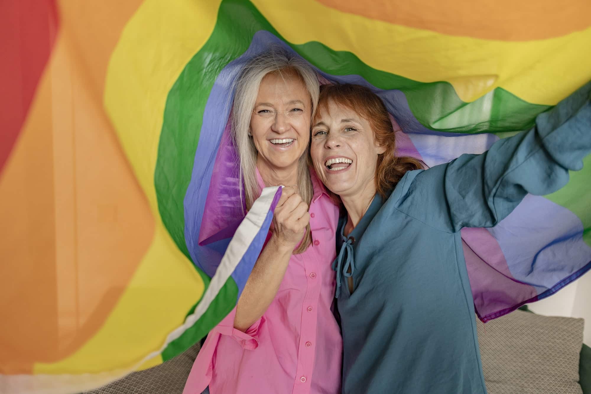 two senior mature women hoist the gay rainbow flag. I support the lgbti, gay, homosexual, bisexual