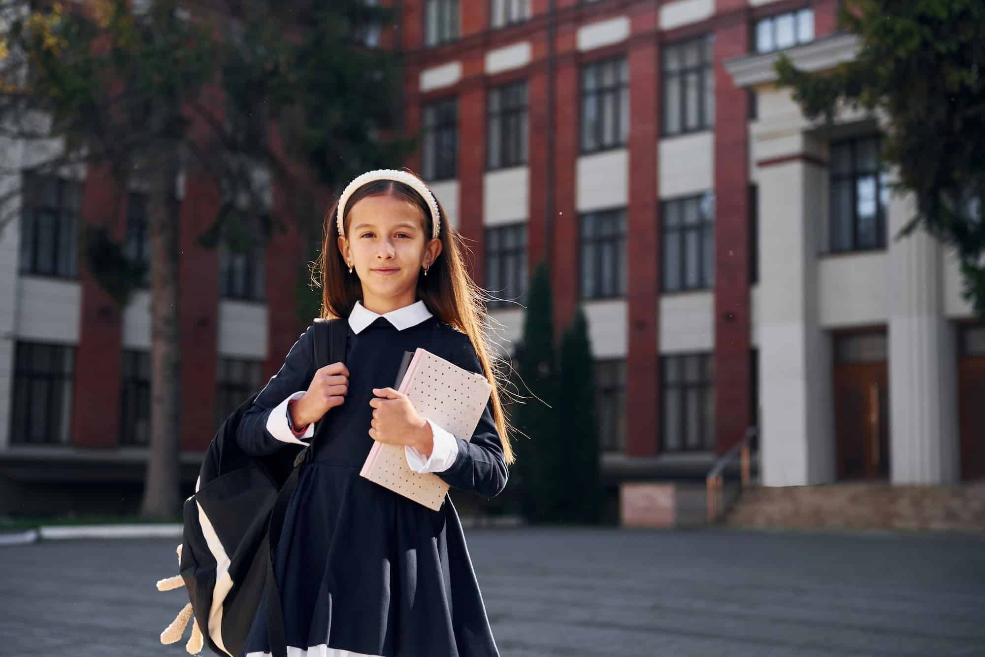 After lessons. Schoolgirl is outside near school building