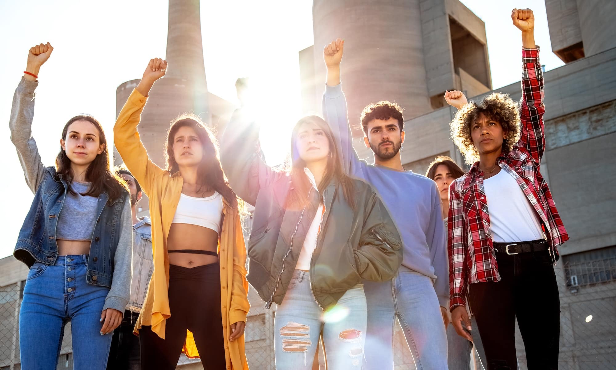 Group of multiracial protesters with fists raised up in the air. Activists protesting on the street.