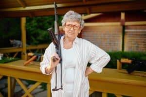 Pretty granny with gun poses in shooting gallery