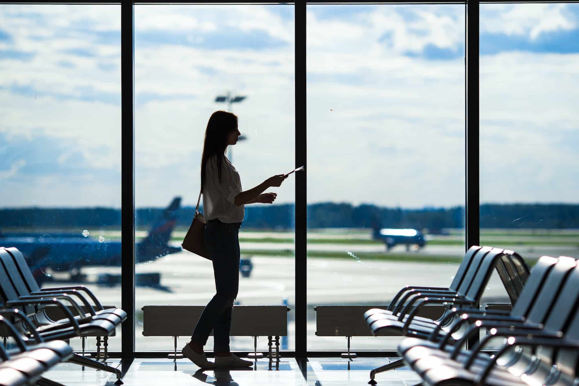 Silhouette of airline passenger in an airport lounge waiting for flight aircraft