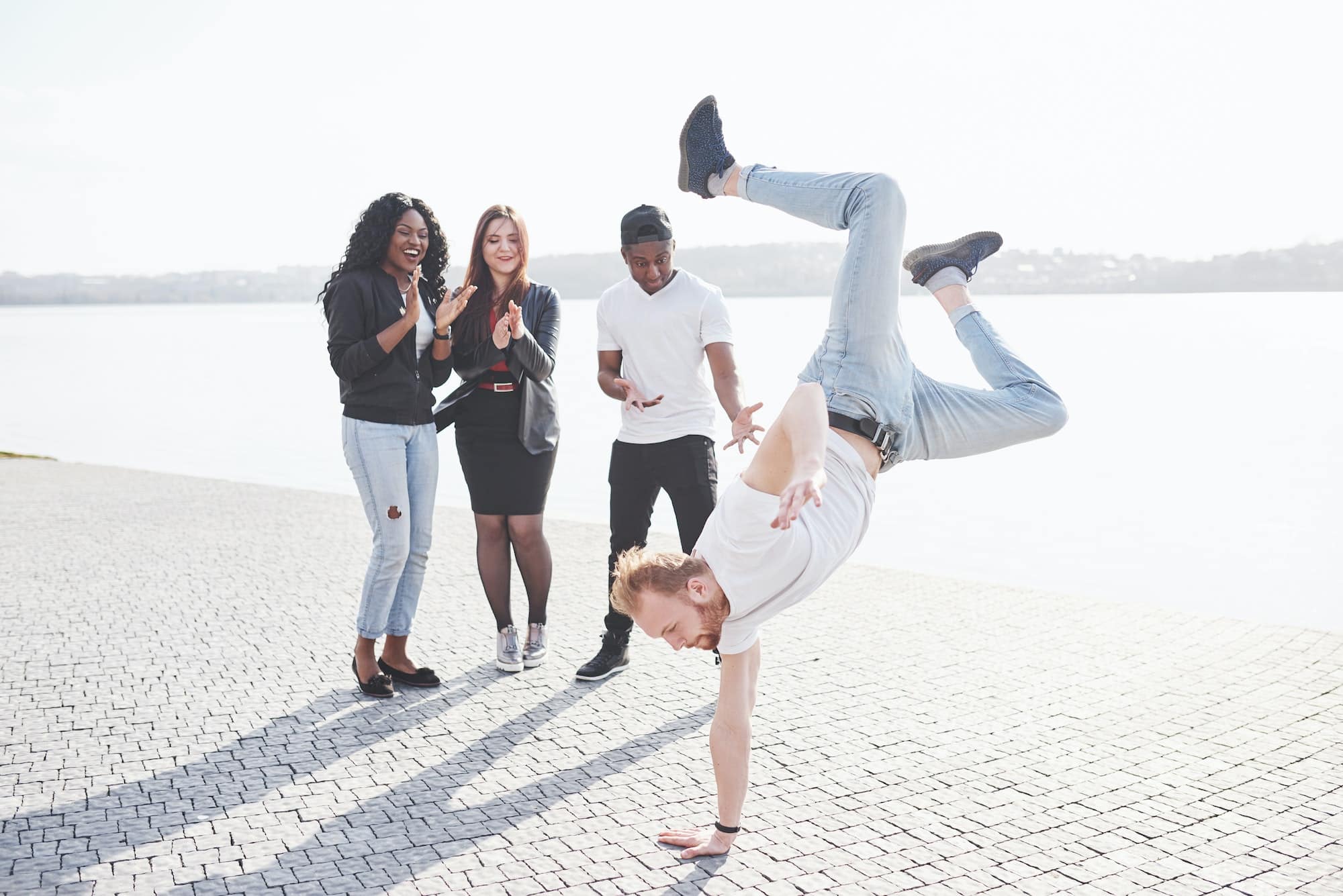 Street artist breakdancing outdoors. Surprised friends applaud