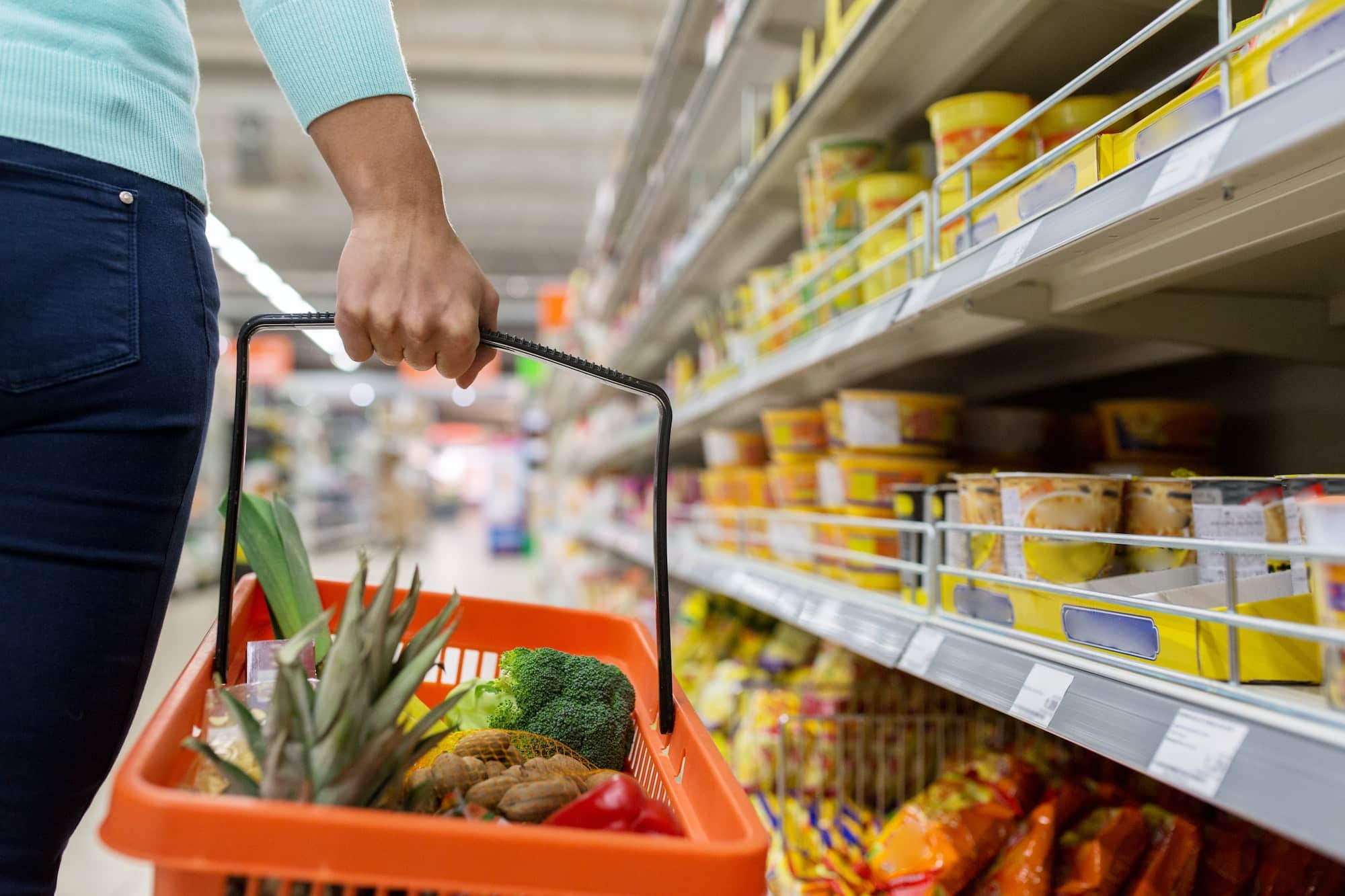 woman with food basket at grocery or supermarket