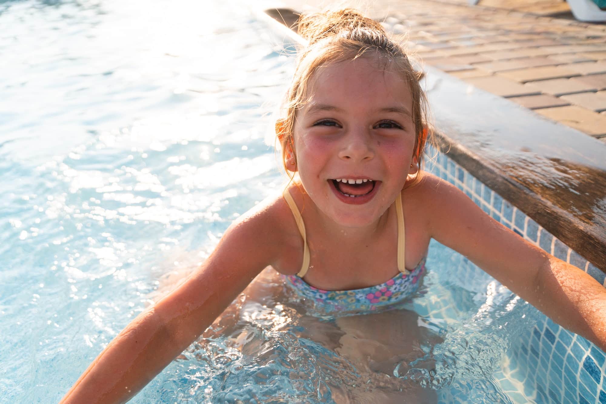 Child girl relaxing at the pool on a sunny hot summer day. Poolside resort concept, heat wave