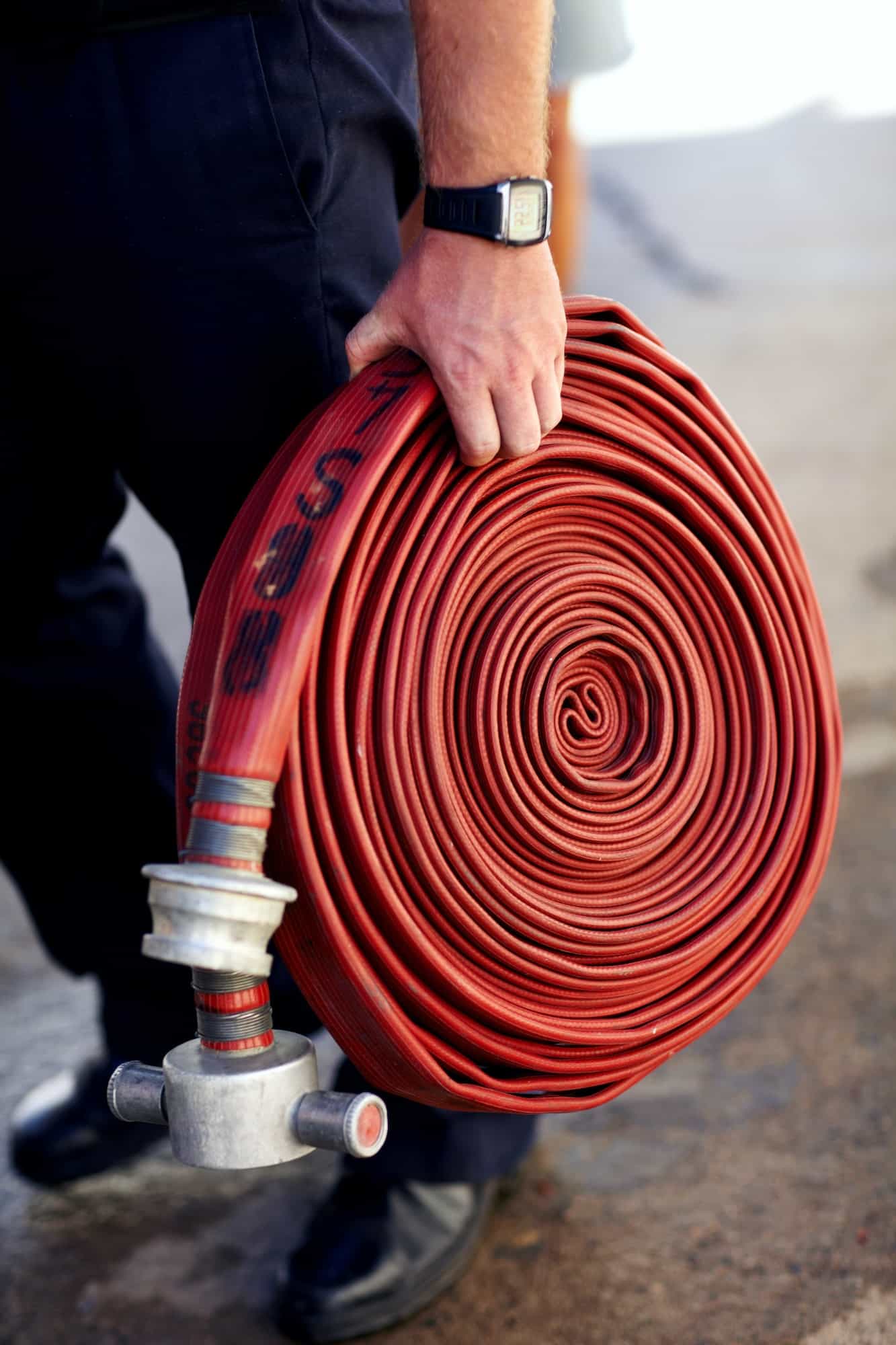 Coiled and ready for action. Closeup shot of a fireman carrying a coiled fire hose.