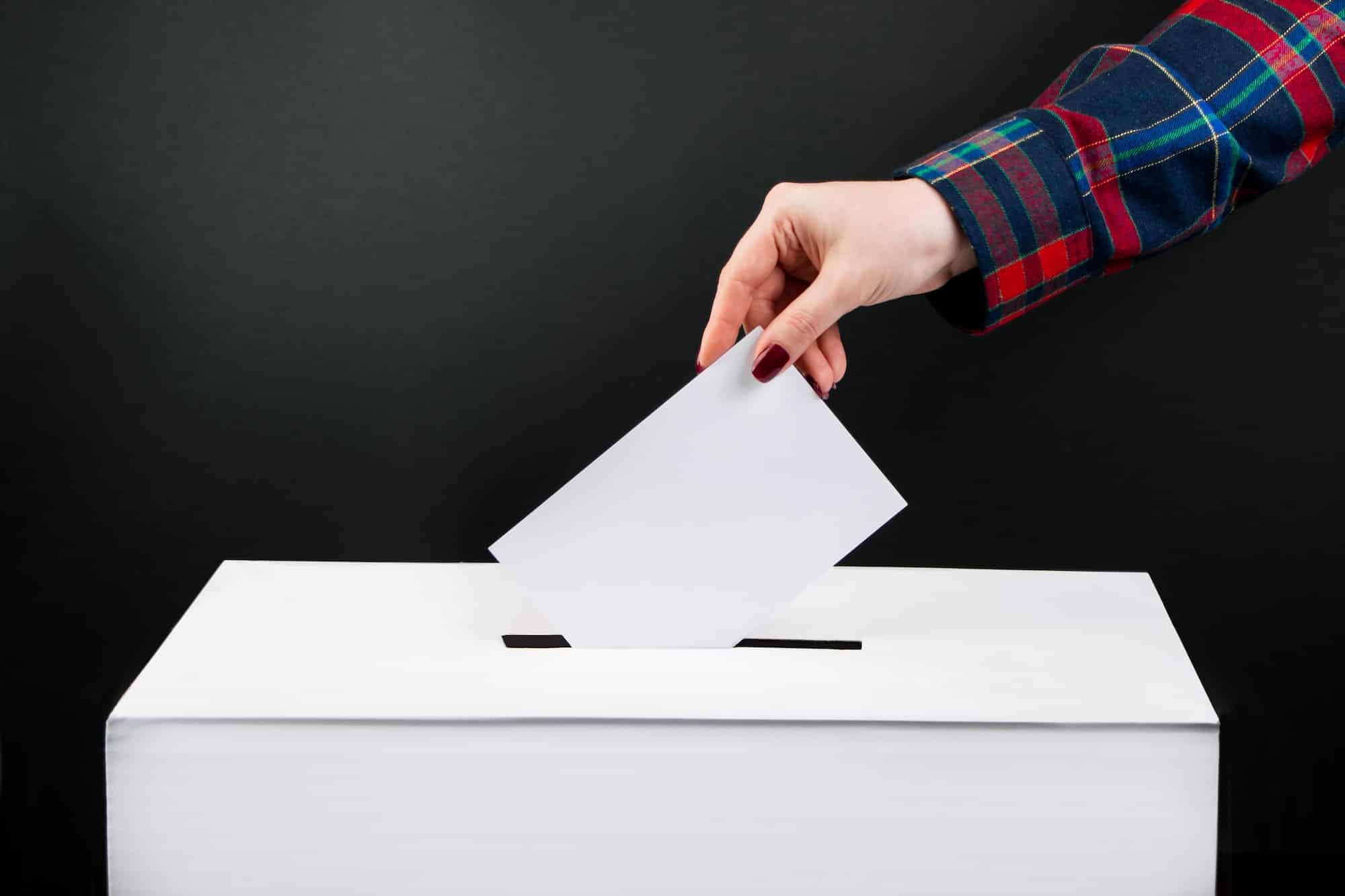 Elections and voting concept. Woman puts ballot paper in a box