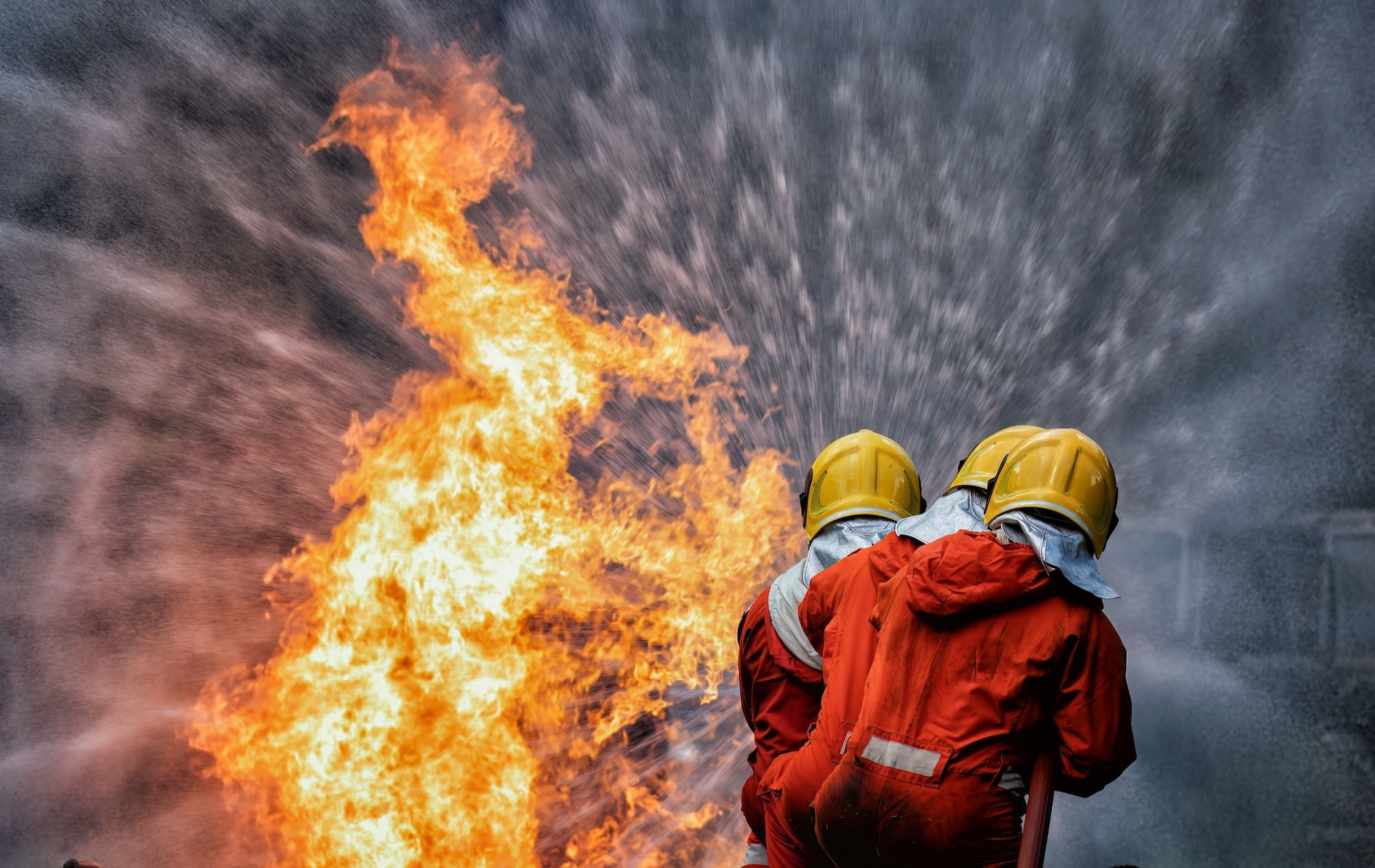 fire fighter team on training with gas and oil fire hold hose spray jet water spray to extinguish