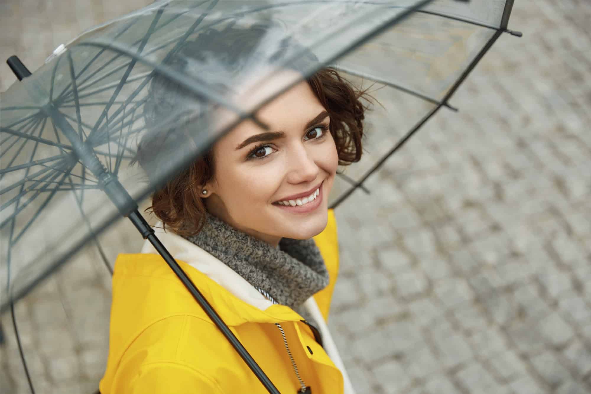 Girl in yellow raincoat with transparent umbrella