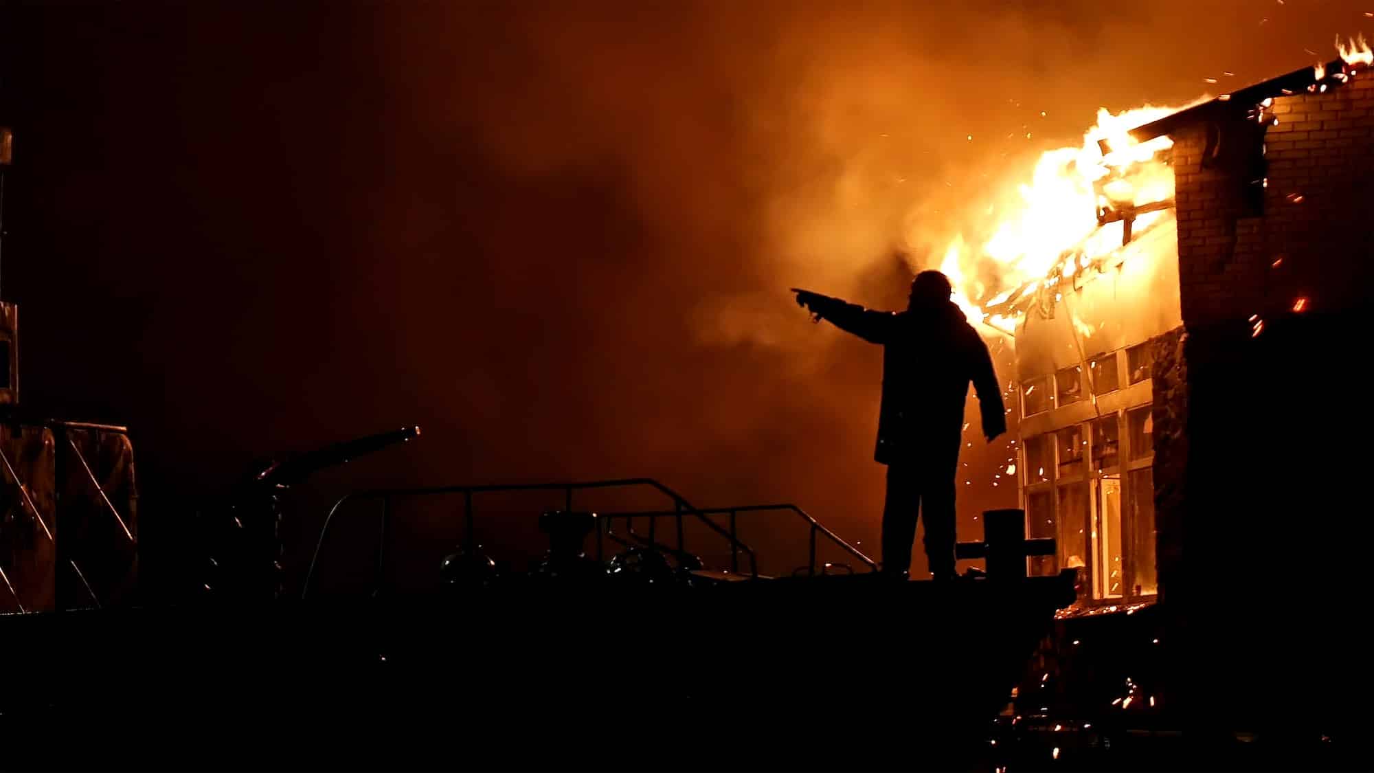 House building on fire at night. Inferno conflagration. Fireman fights fire.