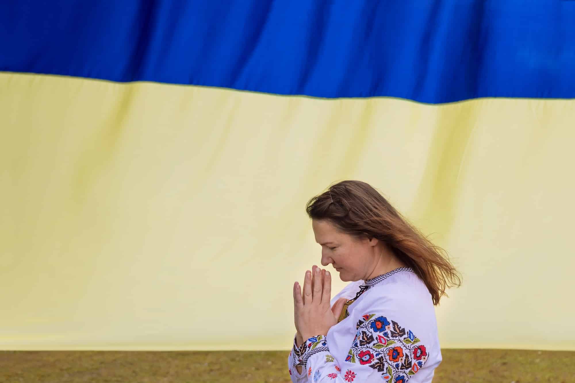 Prayer for Ukraine a young woman prays for Ukraine near the Ukrainian flag