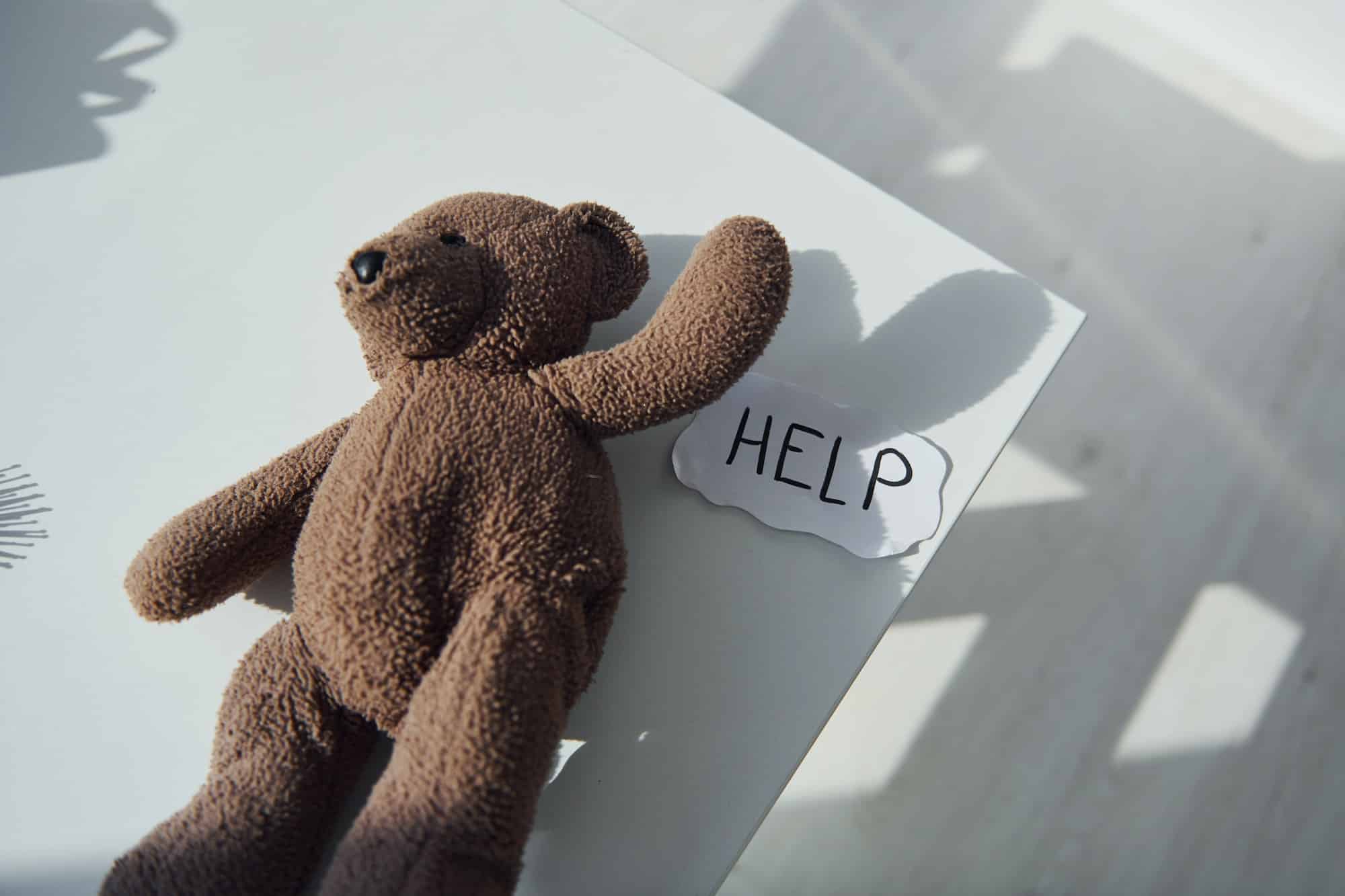 Teddy bear toy lying down on the table. Conception of domestic violence