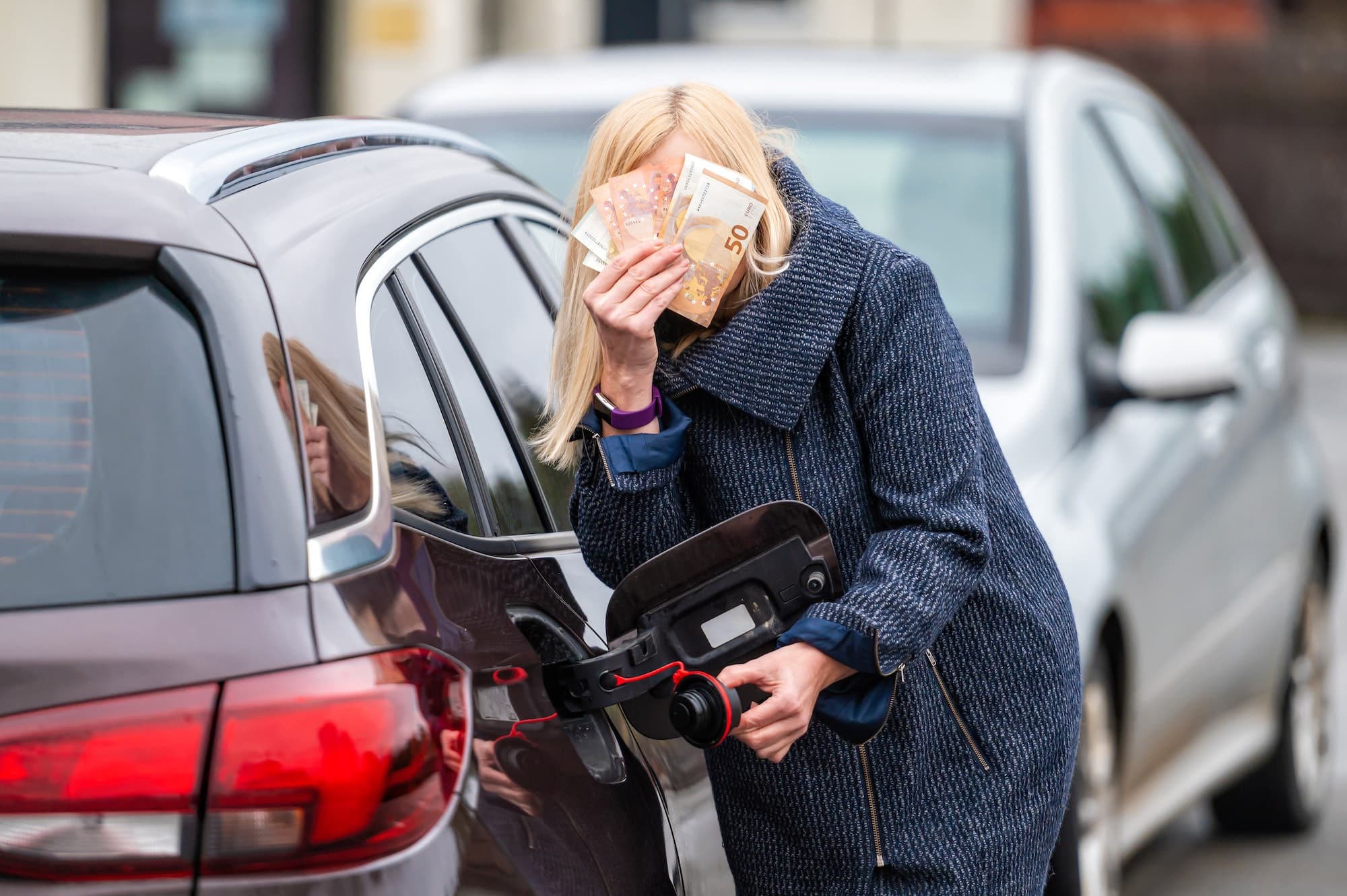 woman with cash near car, the concept of rising fuel prices, expensive fuel