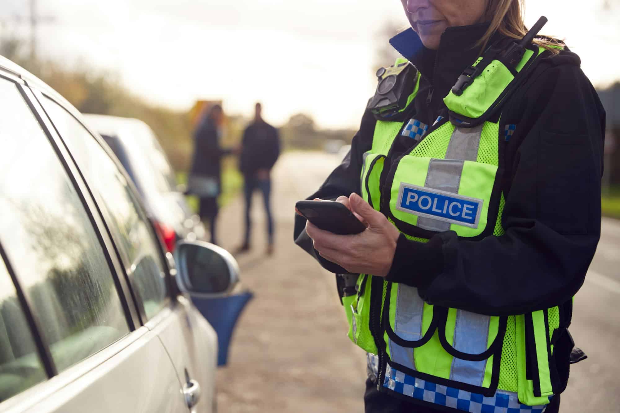 Female Traffic Police Officer Recording Details Of Road Traffic Accident On Mobile Phone