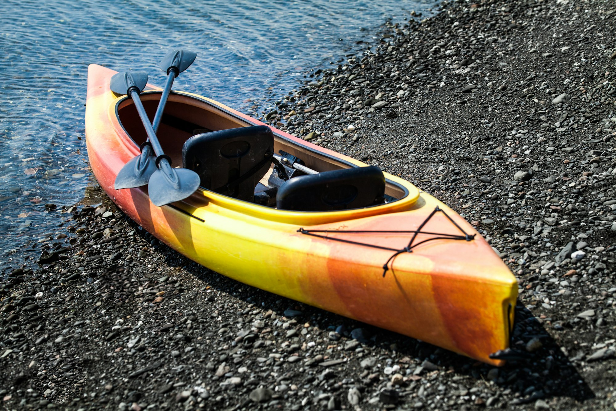 Orange and Yellow Kayak With Oars on the Sea Shore