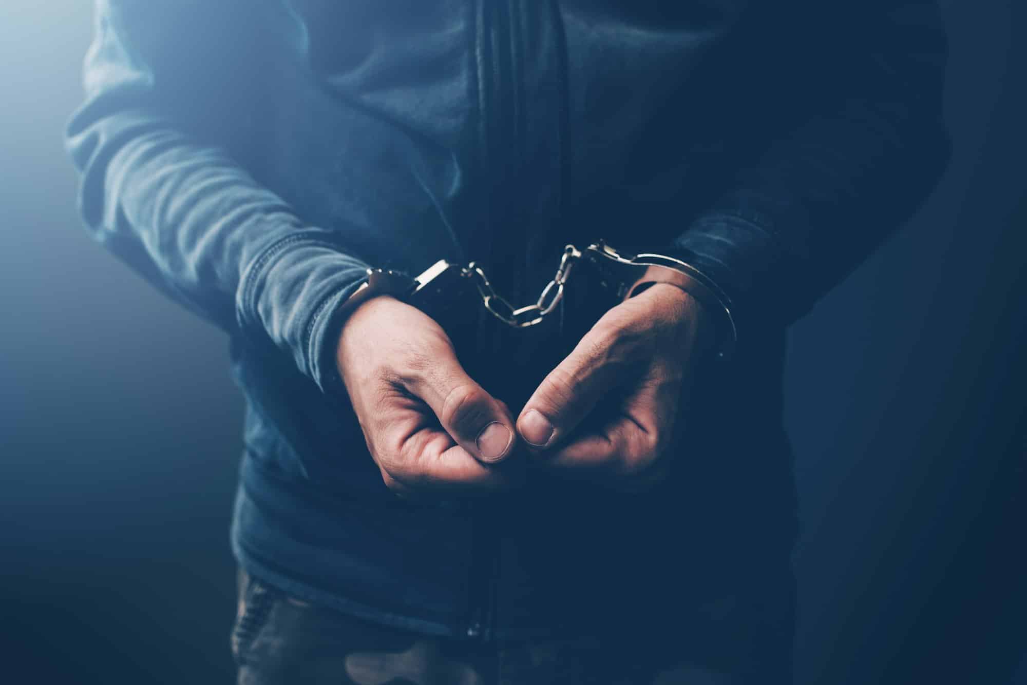 Arrested computer hacker with handcuffs