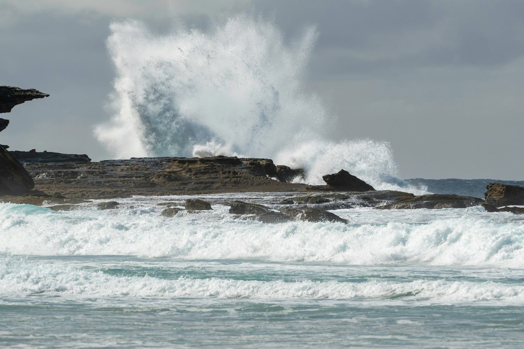 Big wave crashing over the rocks on a day when the waves are really big and rough