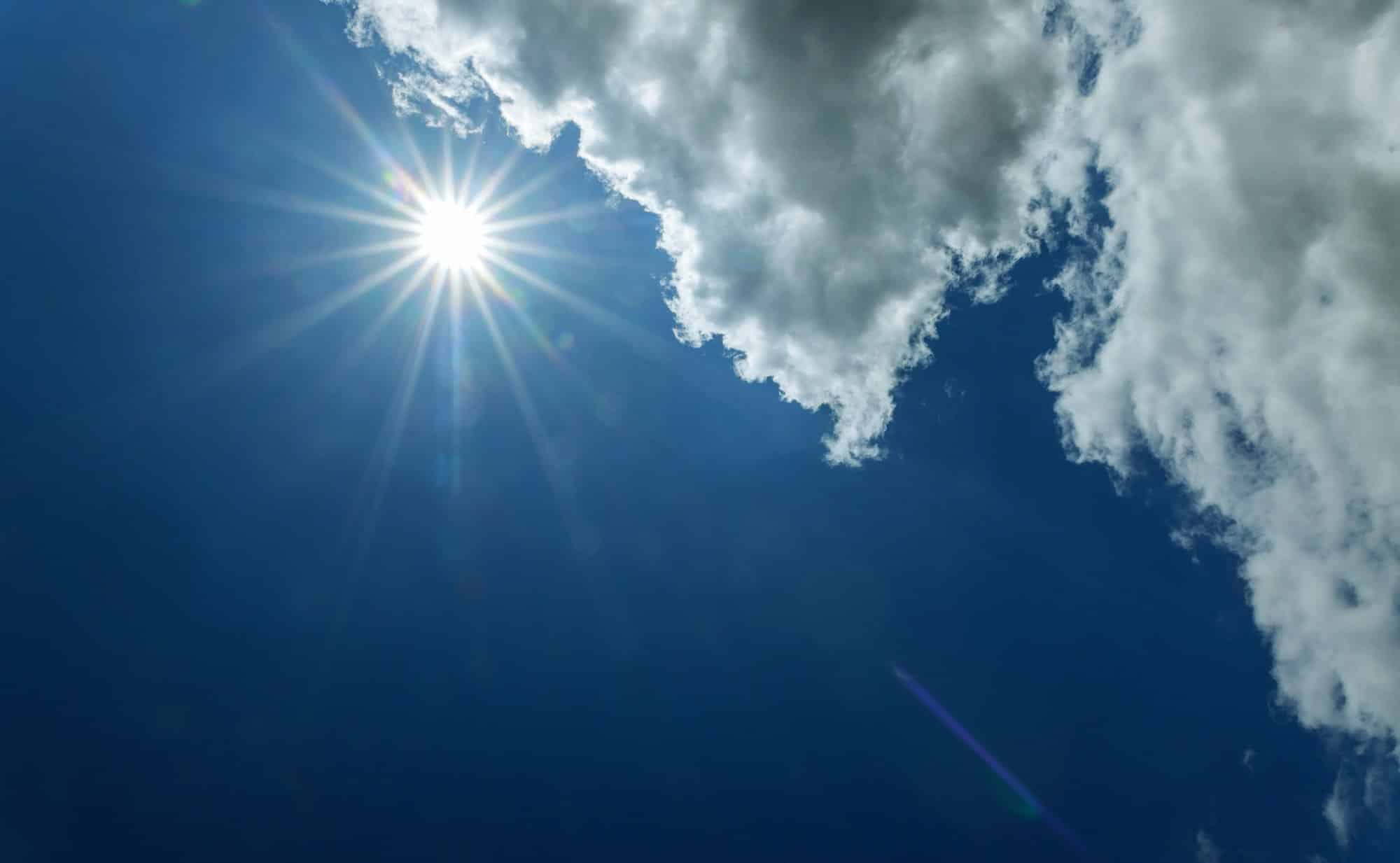 Bright sun on blue dramatic sky with clouds and sun