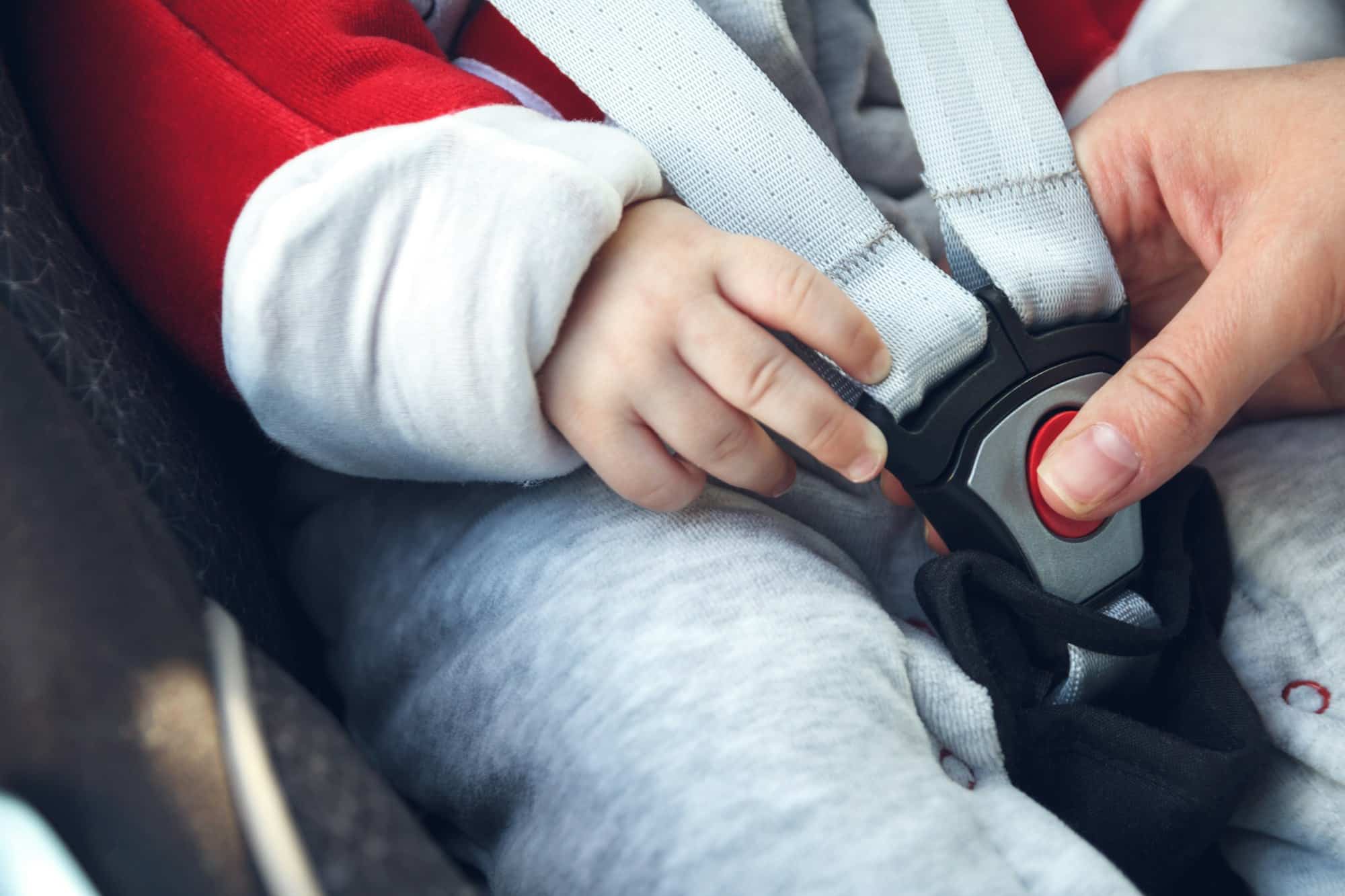 Infant sitting in baby car seat with safety belt locked protection