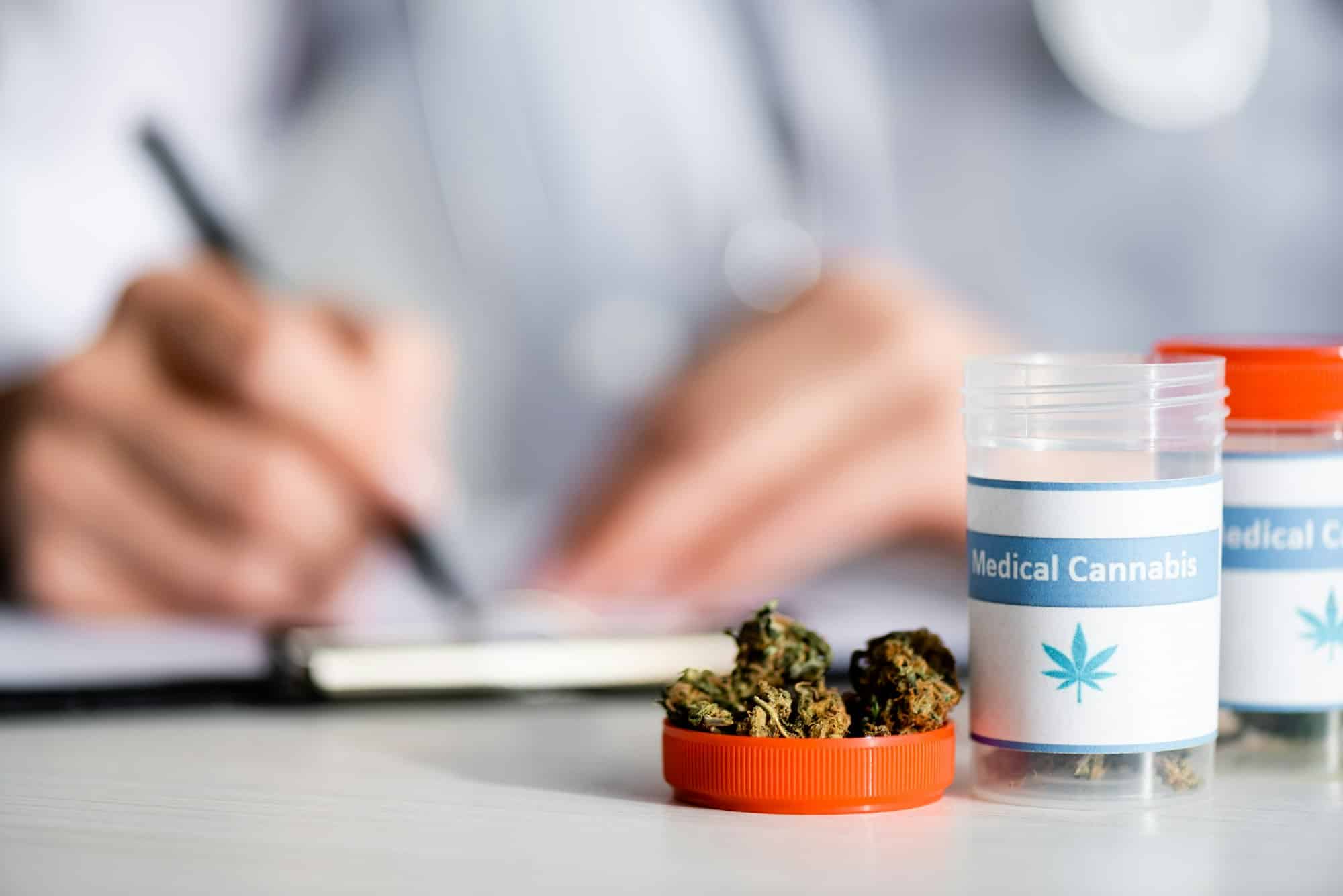 selective focus of dried weed and bottles with medical cannabis lettering near doctor writing