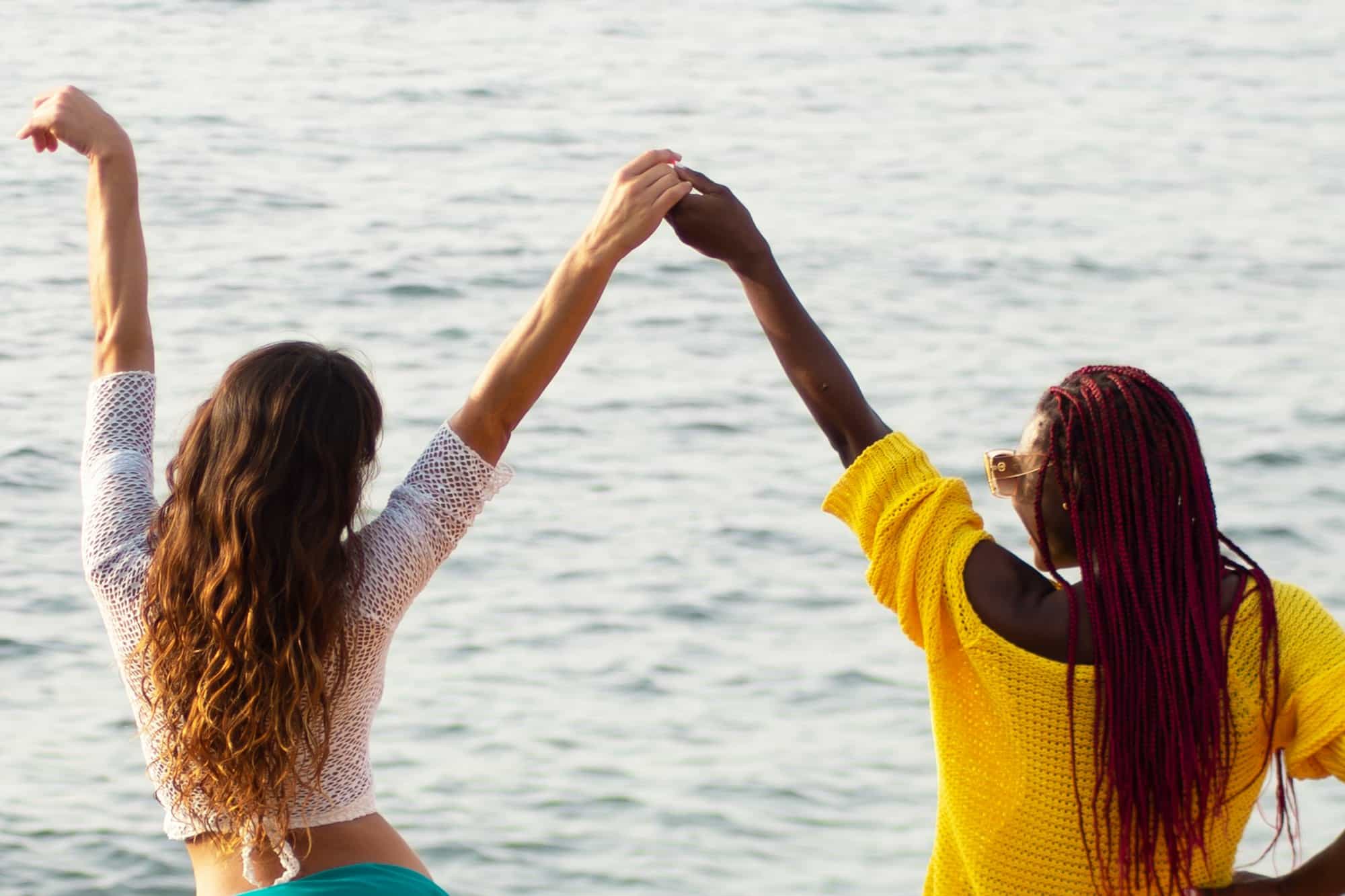 girlfriends, European and African,hold hands against the background of the sea. friendship of People