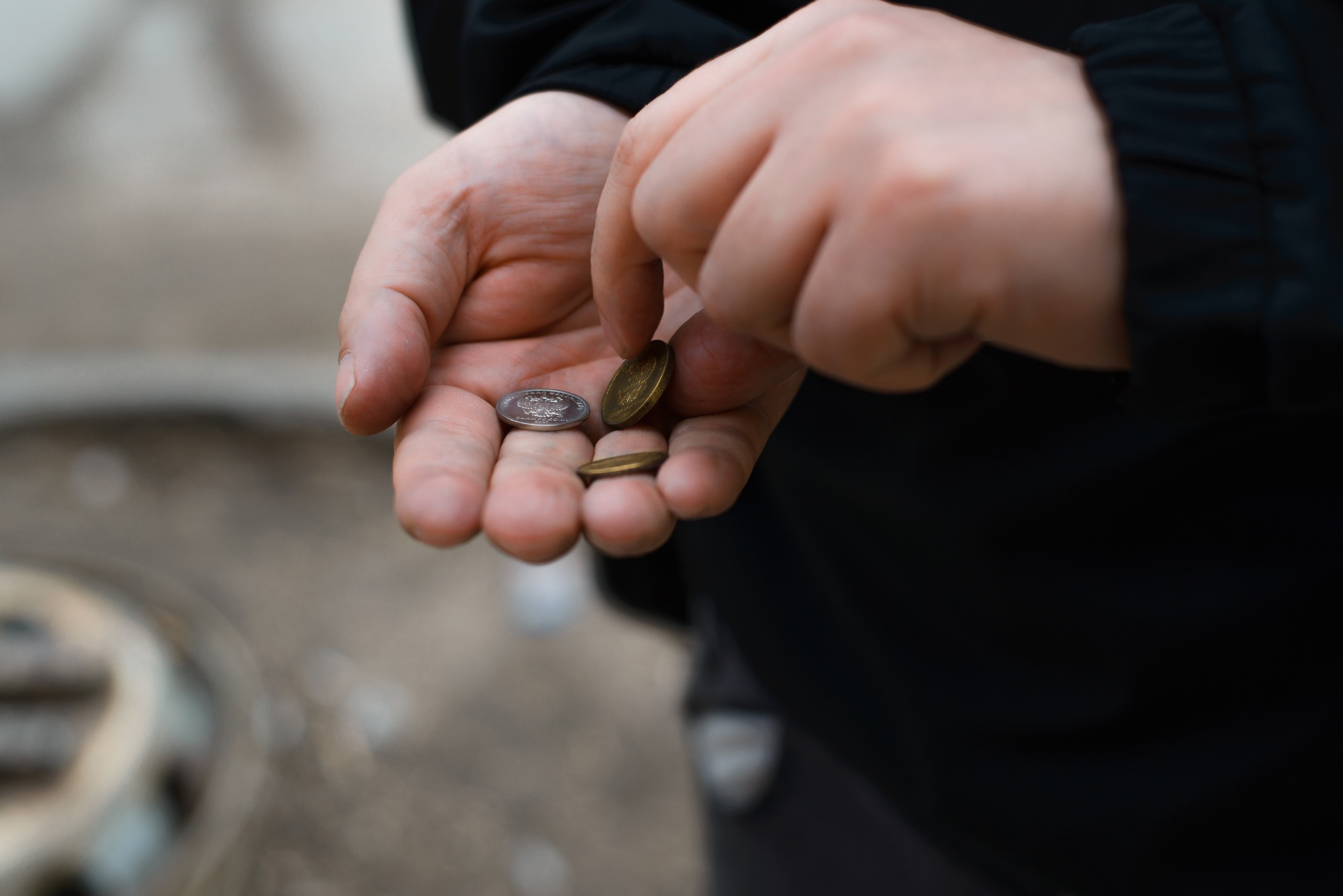 Man counts coins in his palm, outside. Close-up, selective focus. Concept of poverty, misery